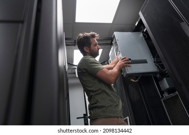 IT engineer working In the server room or data center The technician puts in a rack a new server of corporate business mainframe supercomputer or cryptocurrency mining farm. 