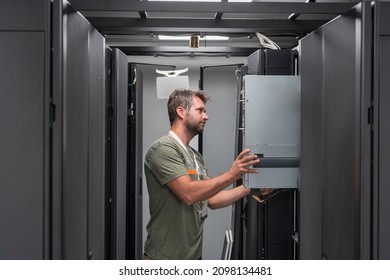 IT engineer working In the server room or data center The technician puts in a rack a new server of corporate business mainframe supercomputer or cryptocurrency mining farm. 