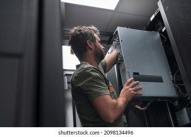 IT engineer working In the server room or data center The technician puts in a rack a new server of corporate business mainframe supercomputer or cryptocurrency mining farm. 