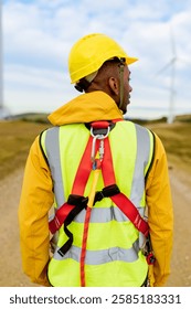 Engineer working at wind power station wearing safety harness and helmet