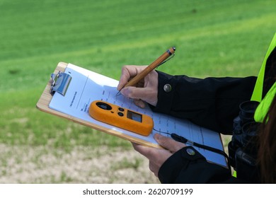 Engineer writing notes about wind energy measurement on clipboard