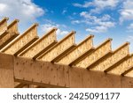 Engineered wood joists or rafters forming the roof of a house under construction