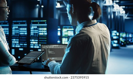 Engineering coworkers programming scripts on tablet and laptop, updating data center equipment designed to accommodate blade servers, networking devices and storage arrays
