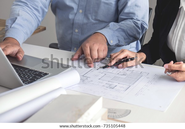 Engineering\
or Creative architect in construction project, Engineers hands\
working on construction blueprint and building model at a workplace\
in office, Building and architecture\
concept.