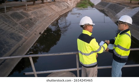 A engineering doing his checking routine. He is wearing hard hat and engineer uniform.Standing by the rail by the dam.Monitor water levels from the heavy rain that has been falling for several days.