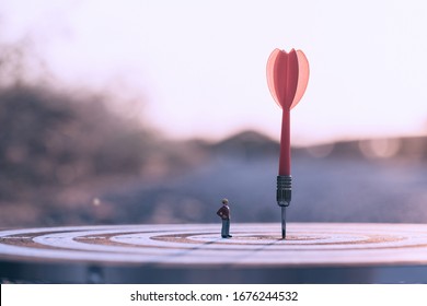 Engineering or foreman standing lookup red dart arrow hitting target centre dartboard on sunset background. Business targeting and focus. - Shutterstock ID 1676244532