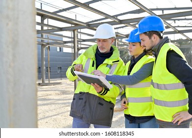 Engineering Instructor Working On Building Site With Apprentice