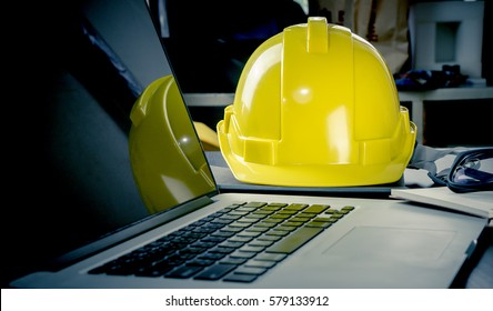 Engineering Laptop computer in construction office and Safety hard helmet for construction office safety concept 