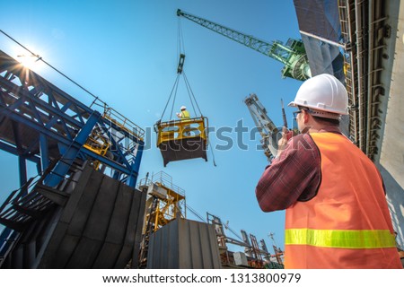 engineering, loading master connecting to gantry crane driver by walkie talkie for lifting safety in loading the goods or shipment, lifting by gantry crane, working at risk on the high level insurance