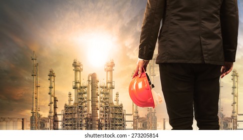 Engineering Man With Safety Helmet Standing In Industry Estate Against Sun Rising Above Oil Refinery Plant 