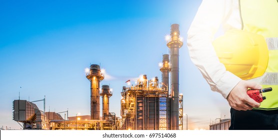 engineering man standing with white safety helmet against oil refinery in petrochemical Aerial view oil refinery night during twilight,Industrial zone,Energy power station background.
