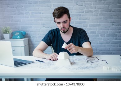 Engineering man testing assembly of pyramid model 3D printer components in office. Engineering tools, technology and innovation concept.