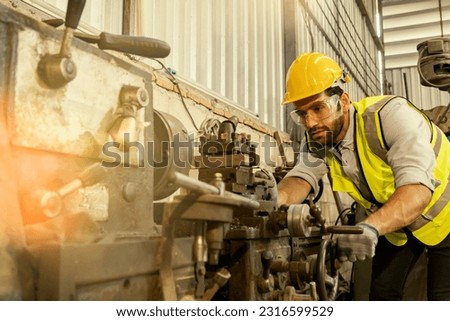 Engineering mechanic wearing safety goggles to prevent accidental scrap metal getting into eyes : Male factory lathe operator wearing safety uniform while machine working : Service metalwork industry.
