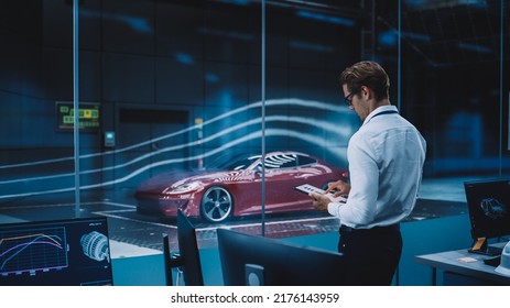 Engineering Research Agency Perform Aerodynamic Testing with a Modern Eco-Friendly Electric Sports Car in a Wind Tunnel. Professional Scientist Works on a Tablet Computer and Changes Testing Options.