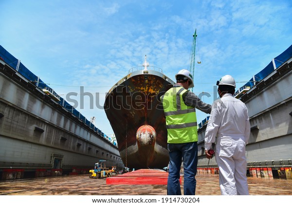Engineering Shipyard working in dry dock\
yard The bulk carrier general cargo ship in dry dock yard,\
recondition of hull repairing and repainting, \
