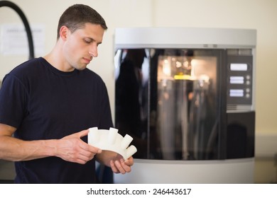 Engineering student holding object printed from 3d printer at the university