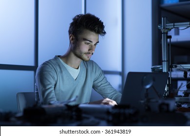 Engineering Student Working At Night In The Lab With A Laptop, 3D Printer In The Background