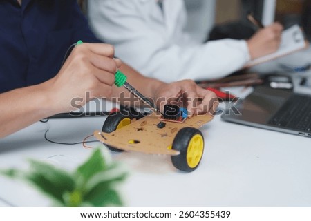 Engineering students are assembling a robot car prototype using a soldering iron and electronic components in a modern laboratory, showcasing innovation and collaboration in robotics education