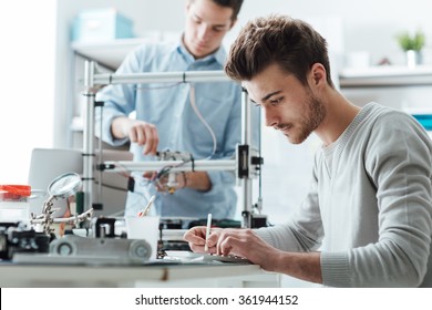 Engineering students working in the lab, a student is using a 3D printer in the background