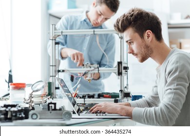 Engineering students working in the lab, a student is adjusting a 3D printer's components, the other one on foreground is using a laptop - Shutterstock ID 364435274