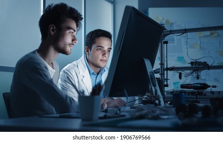 Engineering Students Working In The Lab And Using A Computer, 3D Printer In The Background, Education And Technology Concept