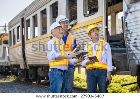 Engineering team inspecting old train carriage at industrial railyard, Railway safety inspectors using digital tablets for maintenance assessment of vintage train