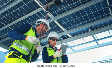 Engineering team measuring solar panel system performance and recording data using digital devices on a modern rooftop facility