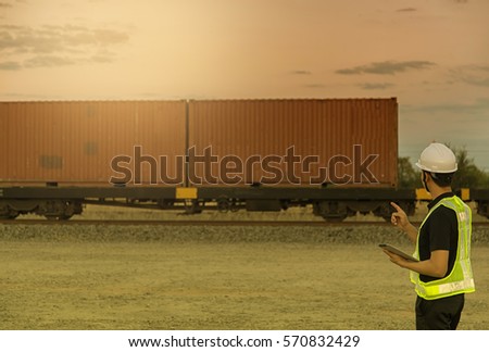 Engineering working hold tablet in front of cargo loading workplace, Freight train