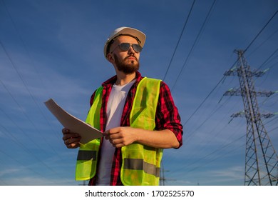 Engineering working on high-voltage tower, check the information on paper at sunset background