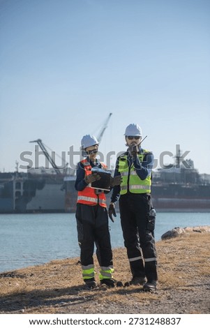 Engineering working at shipyard, Professional logistics monitoring cargo operations at industrial shipyard, transportation, harbor, infrastructure, distribution, freight, commercial shipping.