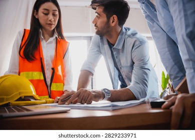 Engineers and architect discussing blueprint with compass during construction planning meeting