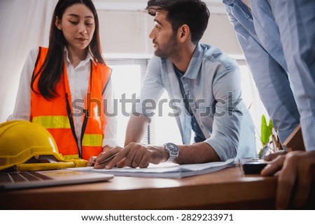 Engineers and architect discussing blueprint with compass during construction planning meeting