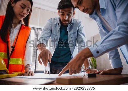 Engineers and architect discussing blueprint with compass during construction planning meeting