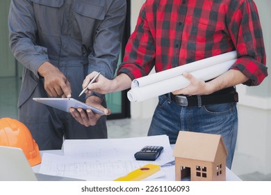 Engineers and architects pointing at digital tablet screens. Two Construction Engineers or Architects discussing at work with digital tablet, laptop and blueprint on construction site.