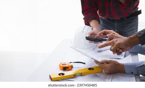 Engineers and architects pointing at digital tablet screens. Two Construction Engineers or Architects discussing at work with digital tablet, laptop and blueprint on construction site.