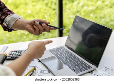 Engineers and architects pointing at laptop screens looking at blueprints to make some modifications, they meet together to plan construction and fixes. Design and interior design ideas. - Shutterstock ID 2052802388