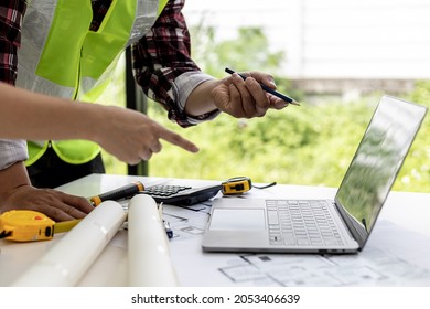 Engineers and architects pointing at laptop screens looking at blueprints to make some modifications, they meet together to plan construction and fixes. Design and interior design ideas. - Shutterstock ID 2053406639