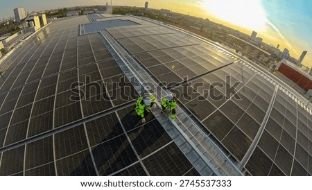 Engineers are checking the solar panels on the roof of a commercial building during golden hour with city skyline in the background