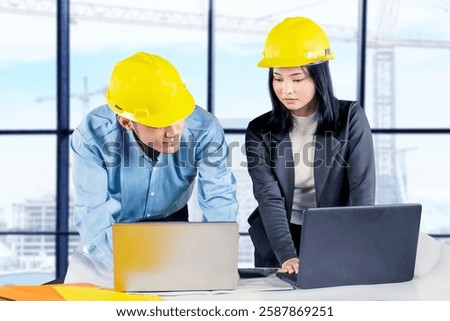 Engineers Collaborating on Construction Project with Laptops in Modern Office
