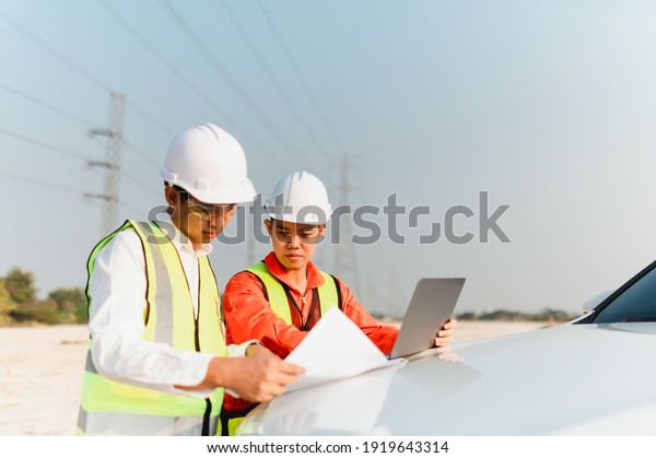 Engineers consult with the foreman to plan the\
installation of solar farms. Engineers discussion with foreman at\
construction site on the car\
bonnet.
