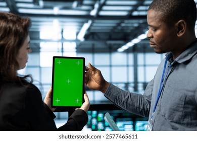 Engineers in data center using mockup tablet, observing analytics, reviewing supercomputer gear health. Server hub IT colleagues chatting, using chroma key device, adjusting system parameters