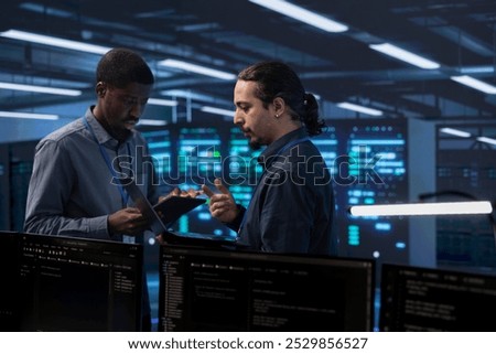 Engineers in data center using tablet and laptop to check for server performance issues arising due to high CPU usage. Server hub workers fixing insufficient memory errors slowing down hardware
