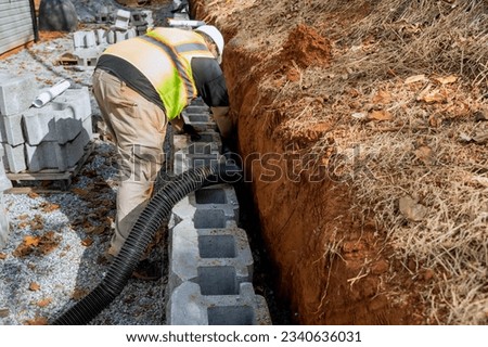 Engineers are devising plan for laying a drainage pipe for rainwater in retaining wall.