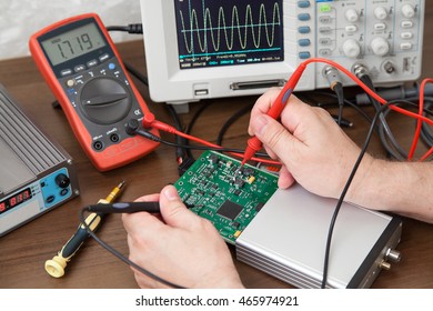 Engineer's hands with the probes testing voltage on the plate - Shutterstock ID 465974921