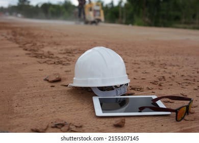 Engineer's Helmet, Tablet And Sunglasses Are Placed On A Concrete Road Construction Site.