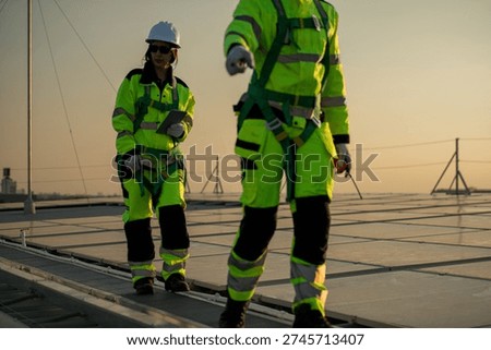 Engineers inspecting the mounting structure of rooftop solar panels during sunset, highlighting safety standards and renewable energy installation