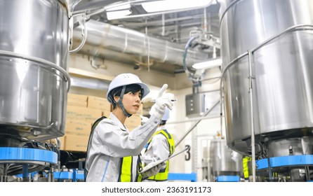 Engineers inspecting stainless steel tanks at the factory. - Powered by Shutterstock