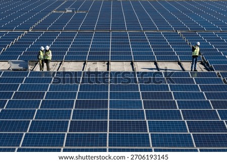 Engineers installing, checking, and maintaining a large solar panel array on a rooftop. Generating clean, sustainable electricity