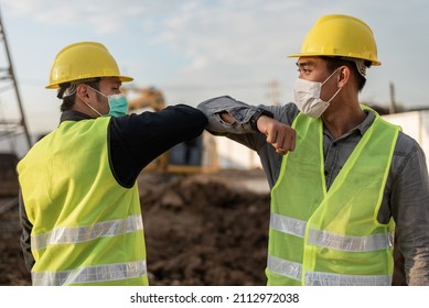 Engineers Man Touching With Elbow In Building Site. Construction Manager And Engineer Man Wearing Face Mask Have A Greeting By Touching The Elbow. New Normal Covid 19 Prevention.