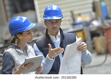 Engineers in mechanical factory reading instructions
